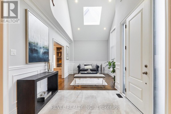 Spacious foyer with a vaulted ceiling, skylight, white wainscoting, and modern furniture. - 475 Poplar Avenue, Ajax
