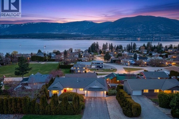 Front view of a white ranch-style house with a dark roof and attached double garage. - 4751 Lakeshore Road Ne, Salmon Arm