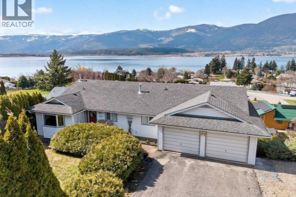 Driveway and double garage of a white ranch-style house with a landscaped yard. - 4751 Lakeshore Road Ne, Salmon Arm