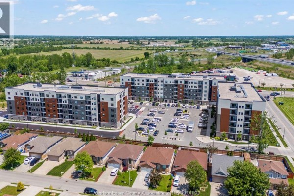 Aerial view of apartment buildings with nearby houses and a highway in the distance. - 4755 Walker Road Unit# 414, Windsor