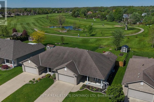 Aerial view of residential homes bordering a golf course with a pond and trees. - 477 1st Avenue, Petrolia