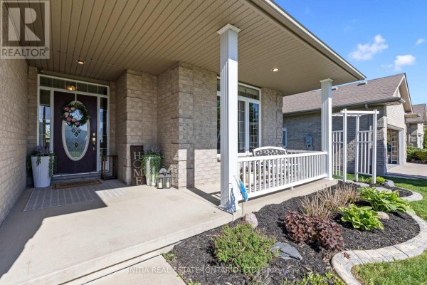 Covered front porch with a white railing, a glass front door, and landscaping. - 477 1st Avenue, Petrolia