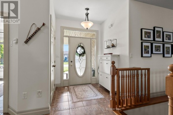 Interior entryway with a tiled floor, a white shoe cabinet, and a staircase with wooden railings. - 477 1st Avenue, Petrolia