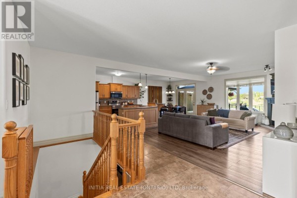 Open concept living space with a kitchen, dining area, and living room, featuring a wooden staircase. - 477 1st Avenue, Petrolia