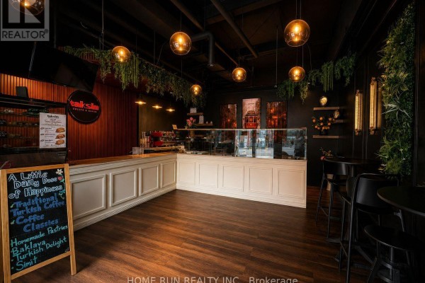 Interior view showing a counter, display cases, and wood-paneled walls with decorative plants. - 477 Bank Street, Ottawa