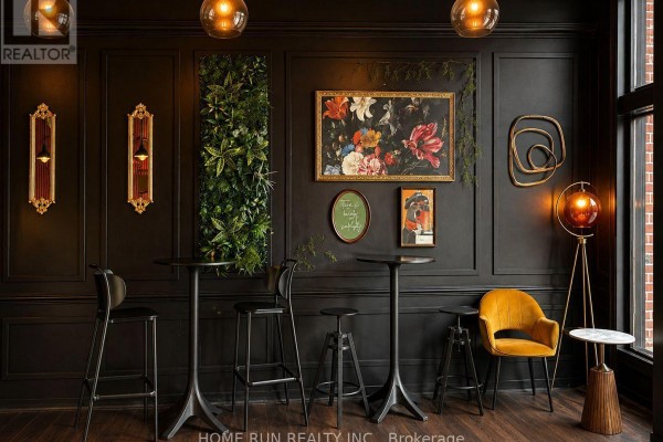 Interior wall detail with dark paneling, tall tables, stools, and framed artwork. - 477 Bank Street, Ottawa