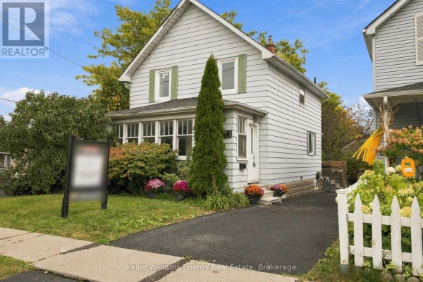 Side view of a two-story house with light grey siding, asphalt driveway, and white picket fence. - 477 Cubert Street, Oshawa