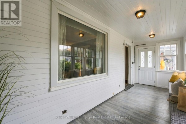 Interior sunroom with white wood-paneled walls, large windows, and grey laminate flooring. - 477 Cubert Street, Oshawa