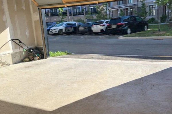View from inside an open garage looking out at parked cars on a paved driveway. - 477 Provident Way, Hamilton