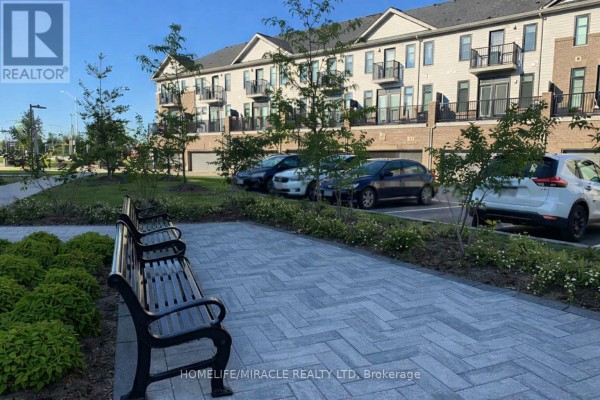 Park area with benches and landscaping facing a row of townhouses and parked cars. - 477 Provident Way, Hamilton