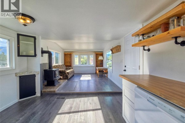Living room area with wood stove, sofa, and view of mountains through the windows. - 4775 Wood Lane Unit# 30, Windermere