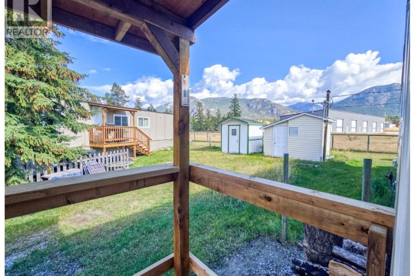View from a covered porch looking out at a yard with sheds and mountains beyond. - 4775 Wood Lane Unit# 30, Windermere