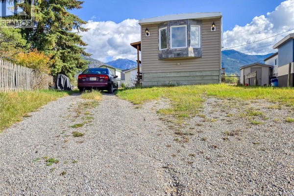 Side view of a mobile home with a car parked in the gravel driveway. - 4775 Wood Lane Unit# 30, Windermere