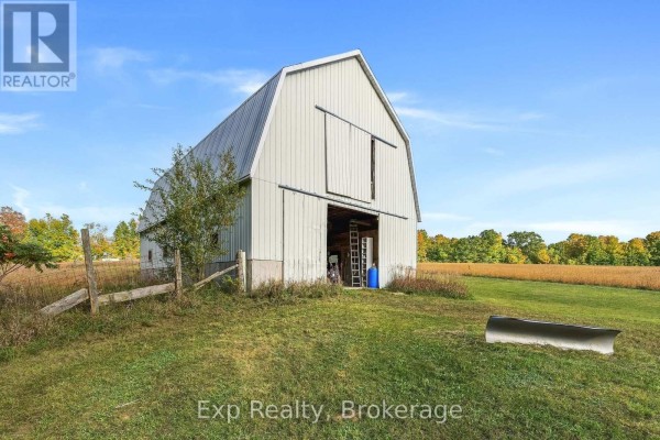 A large white metal barn with an open bay door sits in a grassy field. - 478 Trottman Road, Cramahe