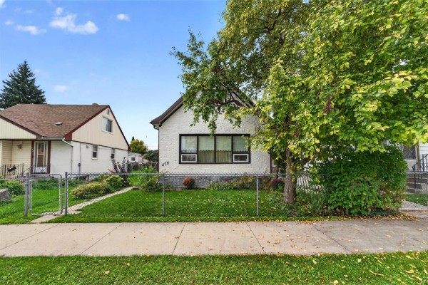 Exterior of a white house with a brown roof and dark trim, next to a sidewalk and lawn. - 478 Washington Avenue, Winnipeg