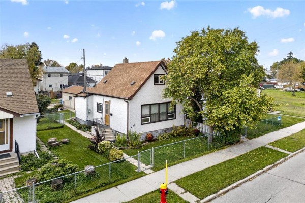 Aerial view of a white house with a brown roof, surrounded by a green lawn and trees. - 478 Washington Avenue, Winnipeg