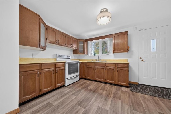 Kitchen with wooden cabinets, yellow countertops, white appliances, and vinyl plank flooring. - 478 Washington Avenue, Winnipeg