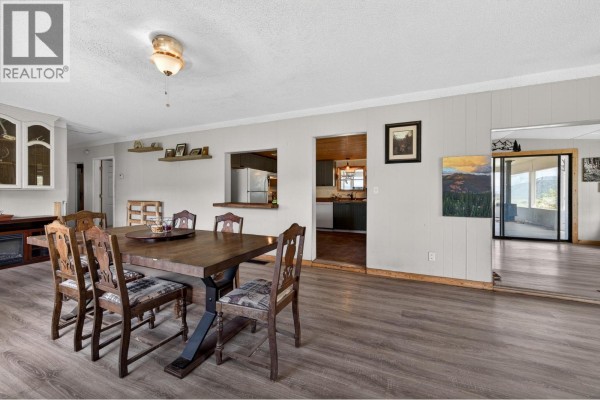 Dining area with a wooden table and chairs, overlooking an open doorway to the kitchen. - 4780 Harrison Road, Pritchard