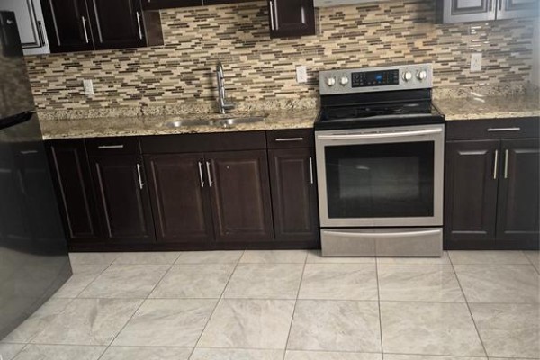 Kitchen with dark wood cabinets, granite countertops, stainless steel stove, and tile backsplash. - 4783 Periwinkle Unit# Lower, Windsor