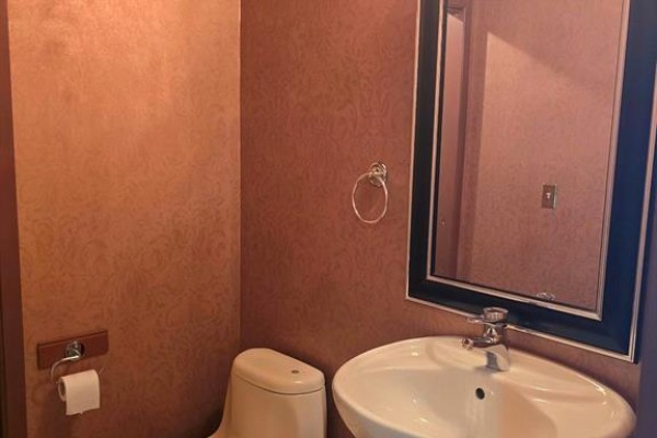 Powder room with patterned wallpaper, toilet, pedestal sink, and a mirror with a black frame. - 4789 Riverside Unit# 1004, Windsor