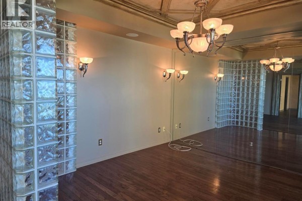 Interior room with dark wood floors, textured glass block walls, mirrors, and ornate chandeliers. - 4789 Riverside Unit# 1004, Windsor