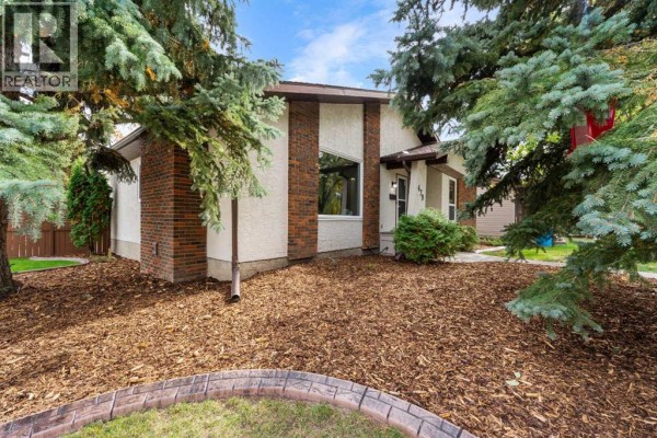 Exterior view of the house with brick and stucco finishes and mature trees. - 479 Bracewood Crescent Sw, Calgary