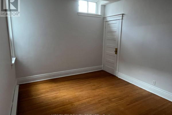 Empty room with hardwood floors and a single window. - 479 Parliament Street, Toronto