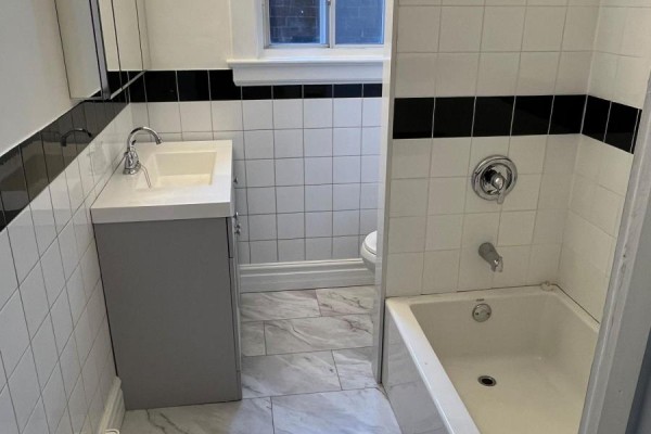 Bathroom with white tiled walls, a vanity, tub, and toilet. - 479 Parliament Street, Toronto