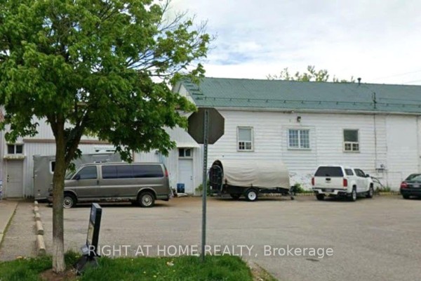 Rear view of white commercial building with loading bay doors and parked vehicles. - 47a Town Line, Orangeville