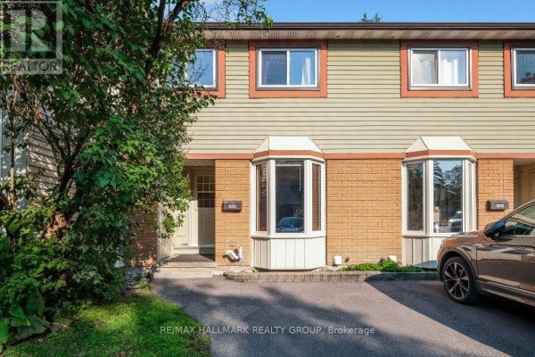 Front exterior of a townhouse with brown brick and beige siding. - 48 - 1005 Cloister Gardens, Ottawa