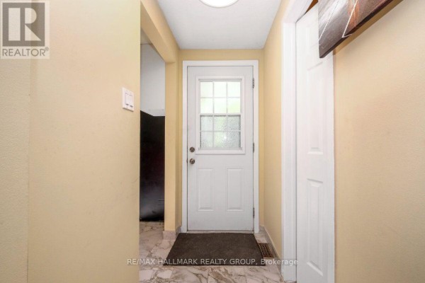 Hallway with beige walls and a white door with glass panes. - 48 - 1005 Cloister Gardens, Ottawa