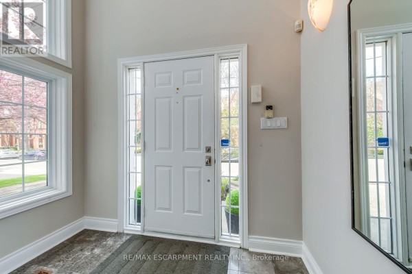 Detailed view of the front door and stone entryway with potted plants and a wreath. - 48 Forsythe Street, Oakville
