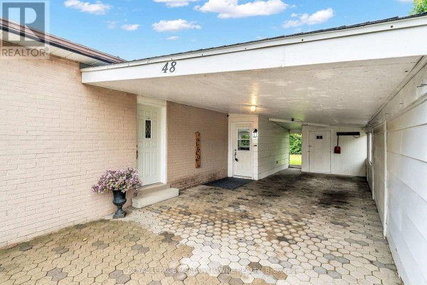 Carport with interlocking pavers, two white doors, and storage access. - 48 Garside Avenue, Whitby