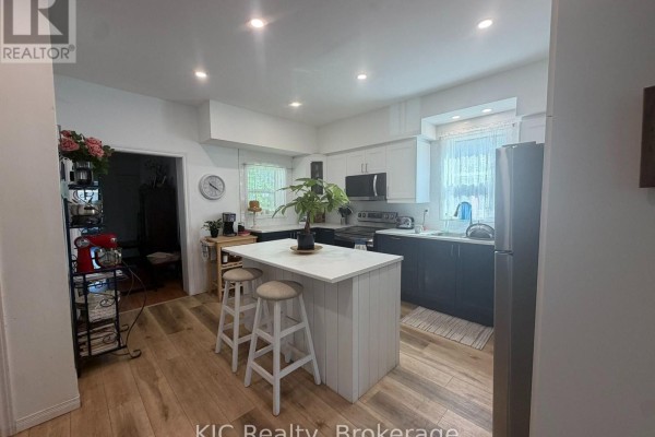 Kitchen with white and dark blue cabinets, stainless steel appliances, and a central island. - 48 George Street E, Havelock Belmont Methuen