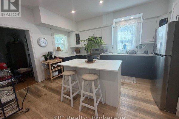 Kitchen featuring white and dark blue cabinetry, stainless steel appliances, and a white island with stools. - 48 George Street E, Havelock Belmont Methuen