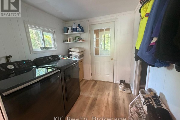 Laundry room with black washing machine and dryer, white paneled walls, and a door leading outside. - 48 George Street E, Havelock Belmont Methuen