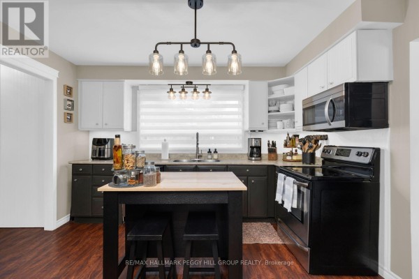 Kitchen with a black stove, stainless steel refrigerator, and an island with seating and storage. - 48 Oren Boulevard, Barrie