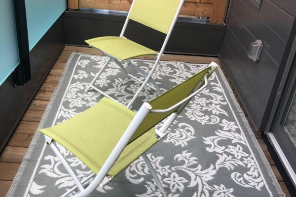 Two green folding chairs on a grey and white patterned rug on a balcony. - 48 Perth Avenue, Toronto