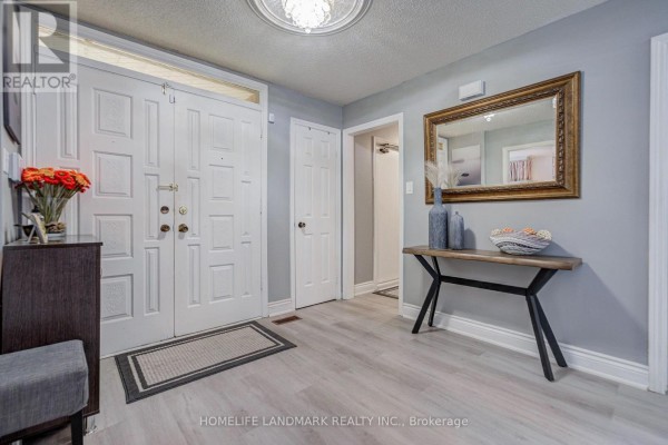 Foyer with double white doors, grey walls, light wood laminate flooring, and a console table. - 48 Purcell Square, Toronto