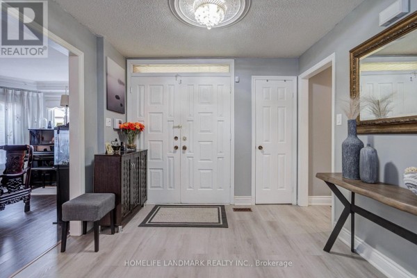 Interior foyer with double white doors, grey walls, light wood flooring, and entry to living room. - 48 Purcell Square, Toronto