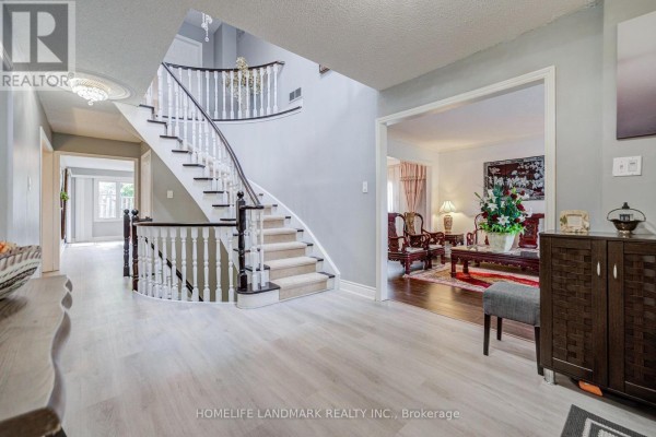 Foyer with curved staircase, light wood flooring, and doorway opening to a formal living room. - 48 Purcell Square, Toronto