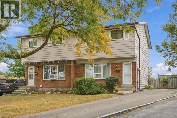 View of the semi-detached house at 48 Raleigh Court, Hamilton with a driveway and lawn. - 48 Raleigh Court, Hamilton