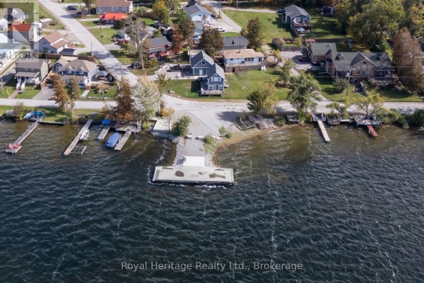 Aerial view of the lakefront property showing multiple docks, boats, and shoreline homes. - 48 Sliverbirch Street, Kawartha Lakes
