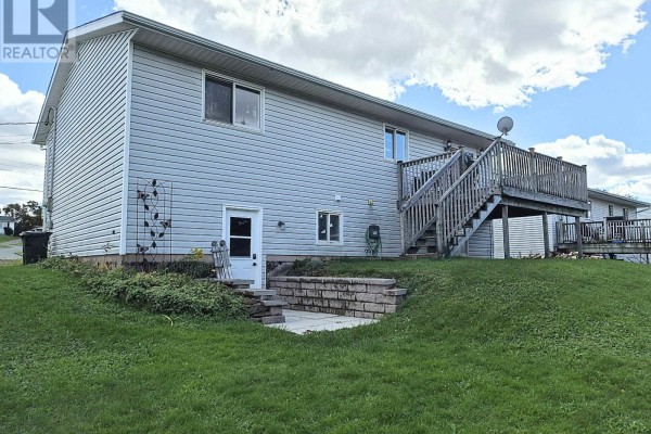 Rear exterior of a light grey house showing a wooden deck with stairs leading down to a backyard patio area. - 48 Townshend Avenue, Amherst