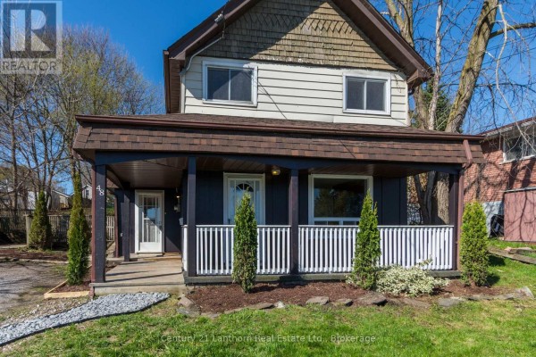 Close-up of the covered front porch with dark siding and white railings. - 48 Wallbridge Crescent, Belleville