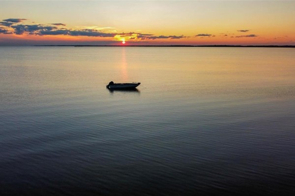 A lone motorboat sits on the water during a vibrant orange and yellow sunset. - 48 Watchorn Landing Road, Moosehorn