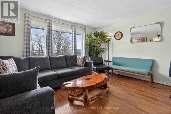 Living room with a large sectional sofa, TV on a wooden stand, and wood floors. - 480 Broderick Street, Tay