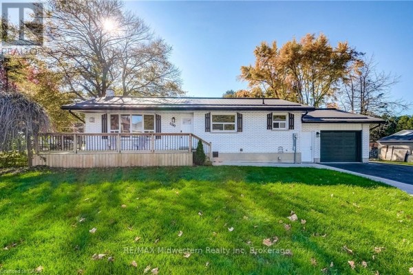 Side view of house with garage, front deck, and green lawn. - 480 Cavan Street, Minto