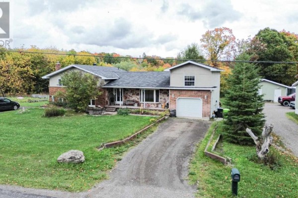 Wide view of a house with a stone and brick facade, single-car garage, driveway, and surrounding lawn. - 480 Moss Rd, Sault Ste  Marie