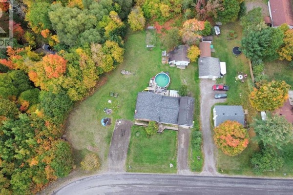Aerial view of a property with a house, above-ground pool, outbuildings, and wooded surroundings. - 480 Moss Rd, Sault Ste  Marie